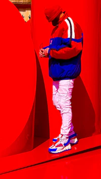 Side-profile editorial portrait of alternative pop singer-songwriter Nevv Evve in a bold red visual set with modern fashion styling.